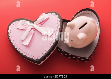 Piggy bank in an empty gift box on a red background. Concept on the topic of saving money for the holidays. Stock Photo