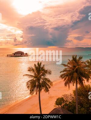 Aerial sunrise sunset beach bay view, colorful sky and clouds, wooden jetty over water bungalow. Meditation relaxation tropical drone view, sea ocean Stock Photo