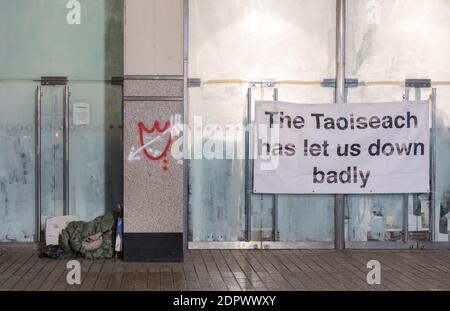 Cork City, Cork, Ireland. 20th December, 2020. Sleeping bags used by  homeless people are rolled up in a shop doorway close to a banner with a political message for the Government, from workers at the Debenhams department store on Patrick's Street in Cork, Ireland.  - Credit; David Creedon / Alamy Live News Stock Photo