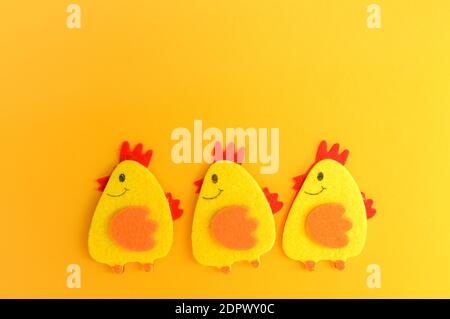 Three cute yellow felt chickens in a row, handmade, diy, kids Easter crafts, copy space, funny handmade idea. Stock Photo