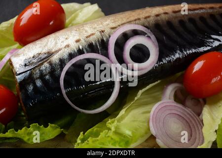 Whole cold-smoked Atlantic mackerel with cherry tomatoes, and red onion on lettuce leaves Stock Photo