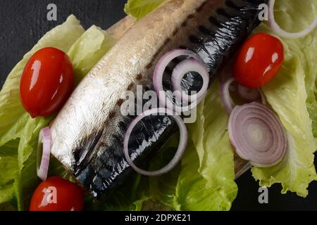 Whole cold-smoked Atlantic mackerel with cherry tomatoes, and red onion on lettuce leaves Stock Photo