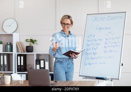 Young female university tutor explaining math, giving remote school class, teaching online lesson on laptop from home Stock Photo