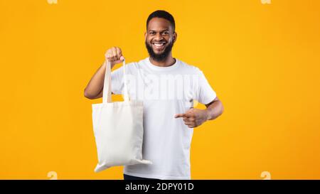 Smiling Black Guy Holding Eco Bag Standing Over Yellow Background Stock Photo