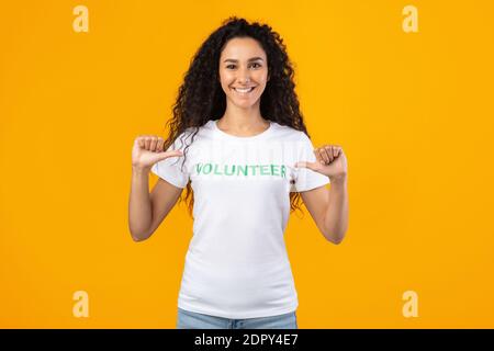 Happy woman volunteer pointing at herself standing over yellow background Stock Photo
