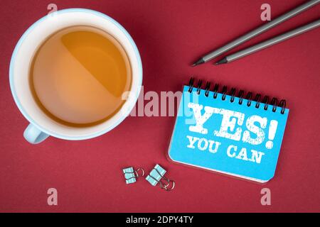 YES YOU CAN. Communication, motivation and recommendation concept. Notebook and cup of tea on a red table Stock Photo