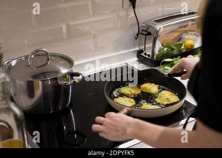 Young charming Swedish woman cooking at home in her kitchen, preparing healthy mediterranean food for her family. Young food blogger doing food prepar Stock Photo