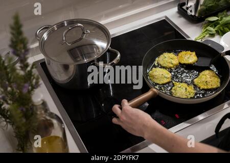 Young charming Swedish woman cooking at home in her kitchen, preparing healthy mediterranean food for her family. Young food blogger doing food prepar Stock Photo