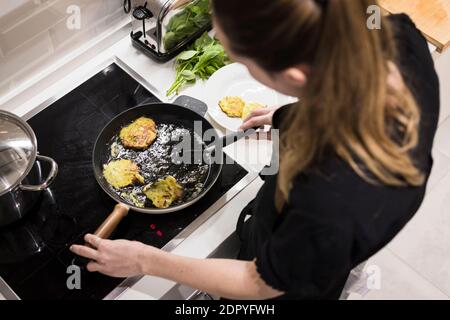 Young charming Swedish woman cooking at home in her kitchen, preparing healthy mediterranean food for her family. Young food blogger doing food prepar Stock Photo