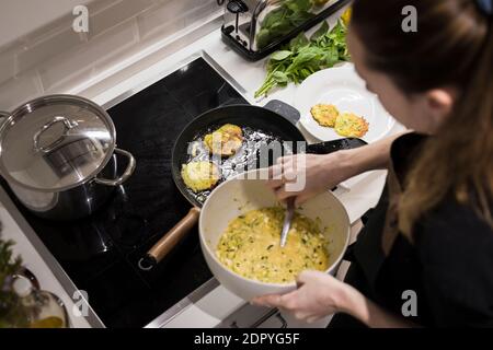 Young charming Swedish woman cooking at home in her kitchen, preparing healthy mediterranean food for her family. Young food blogger doing food prepar Stock Photo