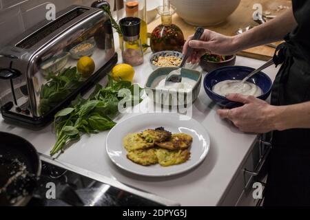 Young charming Swedish woman cooking at home in her kitchen, preparing healthy mediterranean food for her family. Young food blogger doing food prepar Stock Photo