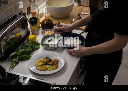 Young charming Swedish woman cooking at home in her kitchen, preparing healthy mediterranean food for her family. Young food blogger doing food prepar Stock Photo