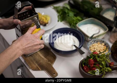 Close up of woman's hands garnishing fresh healthy food with fresh lemon and yogurt. Young food blogger preparing vegetarian food for her contents. Wo Stock Photo