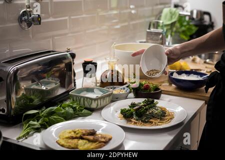 Young charming Swedish woman cooking at home in her kitchen, preparing healthy mediterranean food for her family. Young food blogger doing food prepar Stock Photo