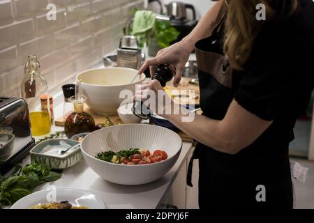 Young charming Swedish woman cooking at home in her kitchen, preparing healthy mediterranean food for her family. Young food blogger doing food prepar Stock Photo