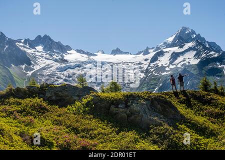 Hikers look at mountain panorama from Aiguillette des Posettes, Aiguille de Tour and Aiguille de Chardonnet, Chamonix, Haute-Savoie, France Stock Photo
