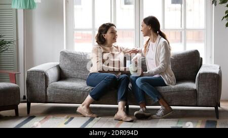 Happy mature mother and grownup daughter relaxing on couch together Stock Photo