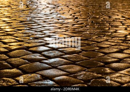Wet cobblestones at night after rain on a street or road surface, bottom view Stock Photo