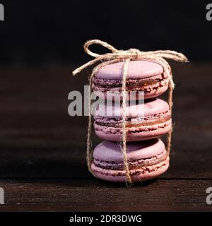 Stacked fig macarons on a wooden table, Flowers in the background Stock Photo