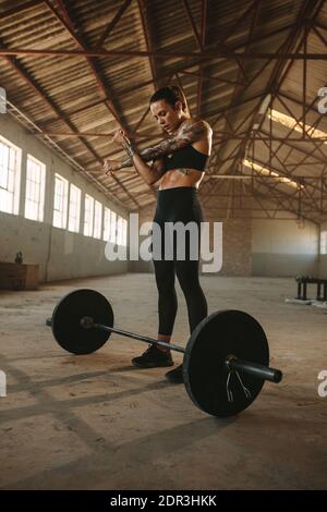 Female doing arms stretching before weight lifting working in fitness space in old factory. Woman Stock Photo