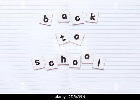 Back to school text written by black printed letters on white sheets of paper on notebook sheet. Education concept. Stock Photo