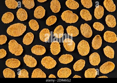 Pattern of corn flakes on black background, top view Stock Photo