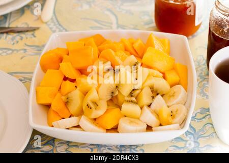 Large plate of fresh exotic fruits for breakfast, mango, bananas, golden kiwi on a table Stock Photo