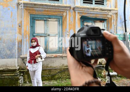 Ipoh, Malaysia. 20th Dec, 2020. A woman wearing a face mask poses for photos on a street in Ipoh, Malaysia, Dec. 20, 2020. Malaysia reported 1,340 new COVID-19 infections, bringing the national tally to 93,309, the health ministry said on Sunday. Credit: Chong Voon Chung/Xinhua/Alamy Live News Stock Photo