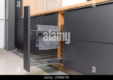 Pull-out kitchen drawer in the kitchen for towels, jars. Modern beautiful kitchen in gray, wooden tones Stock Photo