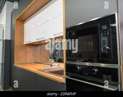 Beautiful stylish minimalistic interior of a modern kitchen in gray and wooden tones with household appliances Stock Photo