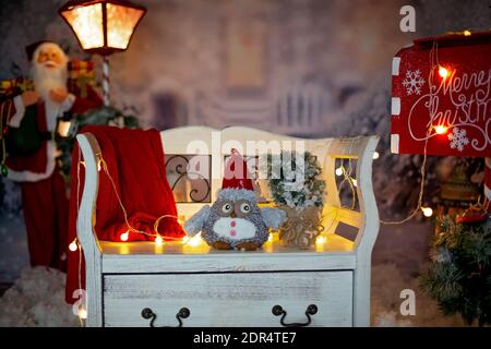 Christmas decoration on an old vintage white bench outside the house in the snow, red lamp and mailbox with lights next to it Stock Photo