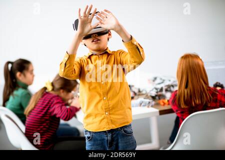 Cute little boy wearing VR virtual reality glasses in a robotics classroom Stock Photo