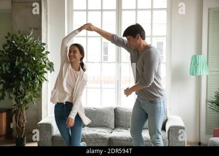 Happy young woman and man holding hands, dancing together Stock Photo