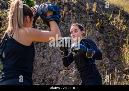 People training during a boxing class outdoor, using boxing mitts with a partner Stock Photo