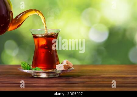 tea pouring from teapot into glass Stock Photo