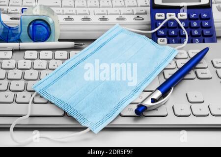 Face Mask in office with PC keyboard Stock Photo