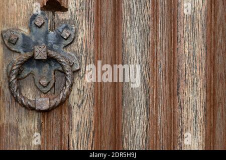 Close-up of rustic wooden door with vertical wood grain and iron metal knocker in vintage style design Stock Photo