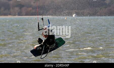 Sandbanks, UK. 20th December 2020.  A kite surfer takes flight in windy conditions on the last weekend before Christmas in Poole harbour at Sandbanks in Dorset. credit: Richard Crease/Alamy Live News Stock Photo