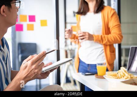 group of business people talking about project and prepare pizza and potato chips for having lunch in corporate together in office Stock Photo