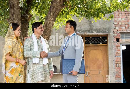 Rural Indian couple with farmer and bank executive shaking hands in village Stock Photo