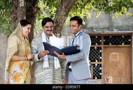 Rural Indian couple with farmer and bank executive shaking hands in village Stock Photo