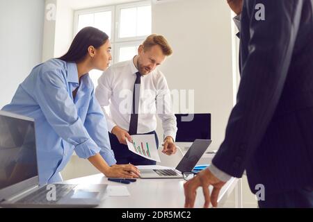 Professional male manager shows infographics to his colleagues during a meeting in the office. Stock Photo