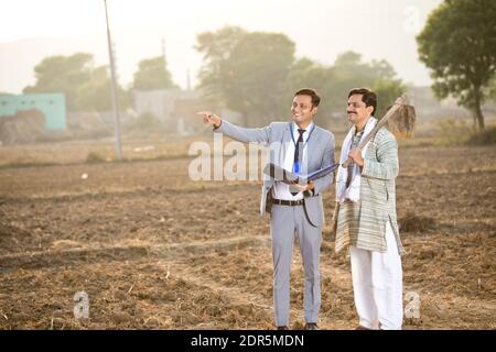 Businessman checking file and discussing with farmer on agriculture field Stock Photo