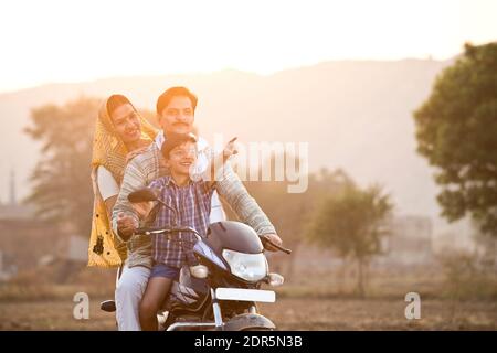 Happy rural Indian family riding on motorcycle Stock Photo
