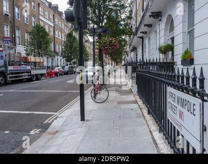 Upper Wimpole Street in the heart of Marylebone Village, London, England. With a red bike parked outside. Stock Photo