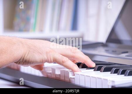 Man hands playing the piano and watching video tutorial on digital tablet computer at home Stock Photo