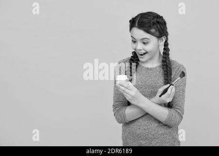 Love yourself more. skincare concept. applying makeup on a healthy skin. child make up products. copy space. studio shot of girl doing make up. surprised teen girl doing makeup using powder brush. Stock Photo
