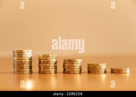 Close up of stacks of many GBP one pound coins decreasing in size as money going down symbolising the effects of inflation, UK Stock Photo