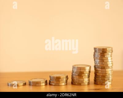 Close up of stacks of many GBP one pound coins increasing in size as money going up symbolising saving wealth, UK Stock Photo