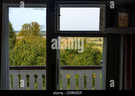 View on an apple orchard through an old window with focus on the trees. Countryside view with trees in rich golden and green colors. Stock Photo